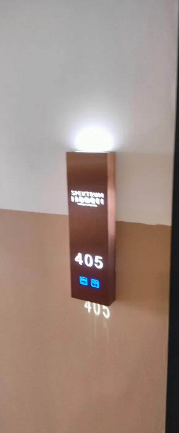 Backlit bronze door sign showing room number 405 with two small status icons