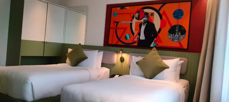 Twin guest room with two beds, green panelling and a large orange artwork