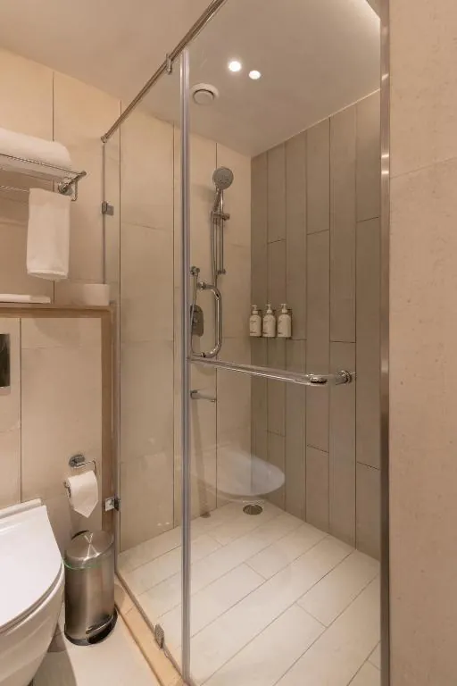 Hotel bathroom with a glass-enclosed shower, towel rack and wall-mounted toiletries