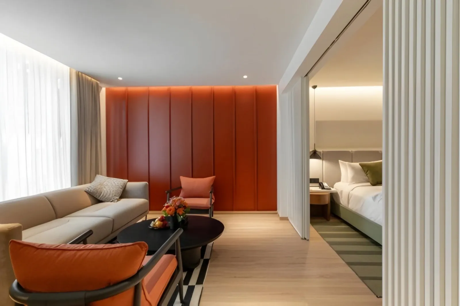 Hotel suite living area with orange wall panels and a sliding screen opening to the bedroom