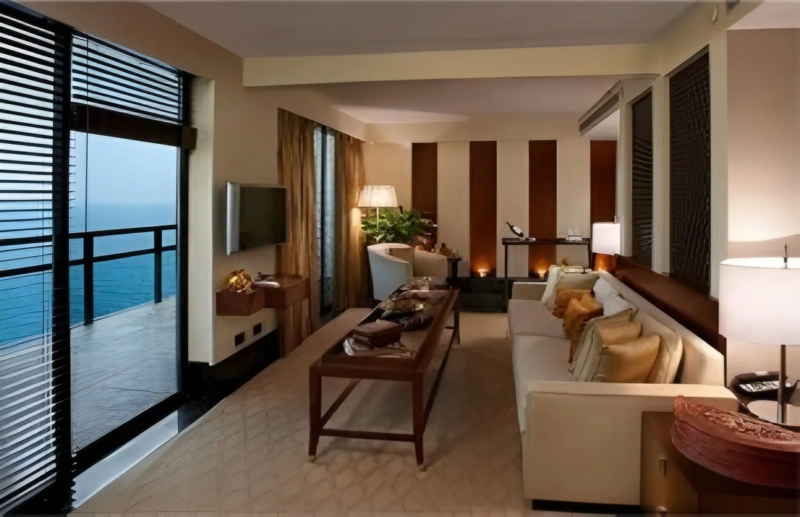 Resort suite living area with a cream sofa, wooden coffee table and balcony doors opening to the sea